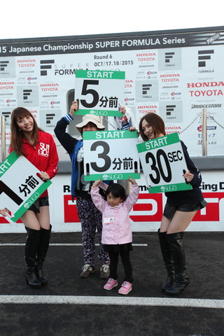 キッズピットウォーク: カウントダウンボードを持つ子どもとレースクイーン