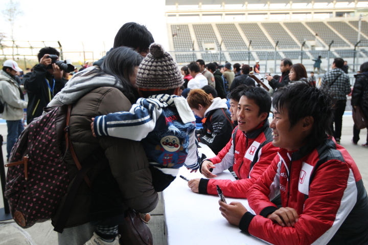 サインする伊沢拓也と塚越広大のDOCOMO TEAM DANDELION RACINGコンビ