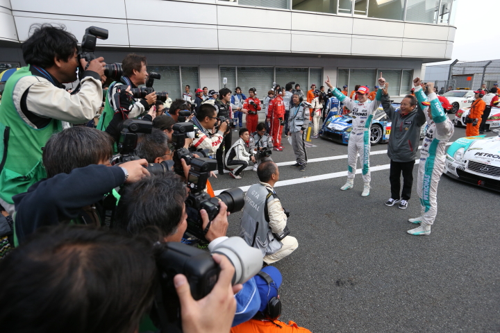 カメラマンに囲まれるGT500クラス優勝の中嶋一貴／ジェームス・ロシター組、関谷正徳監督
