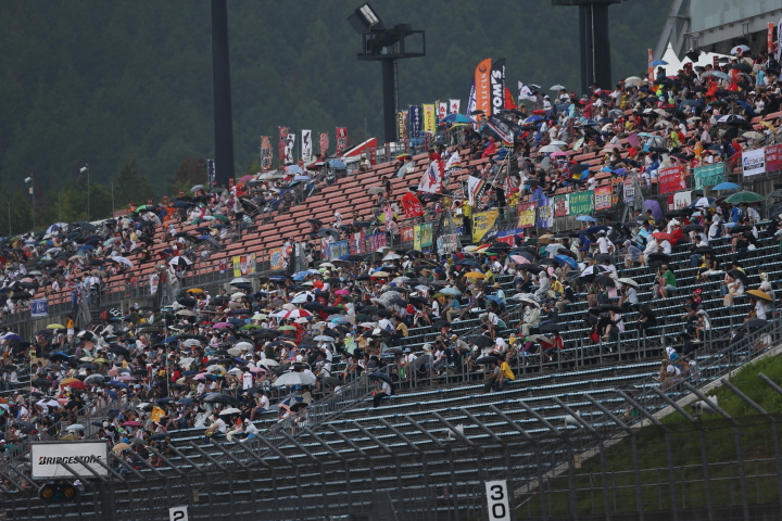 スタート直前に空から雨、傘が開くメーンスタンド