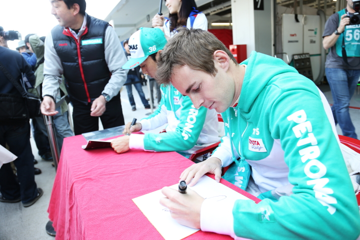 サインするジェームス・ロシターと中嶋一貴（PETRONAS TEAM TOM’S）