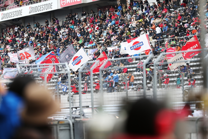 グランドスタンドではニッサンの旗が打ち振られる