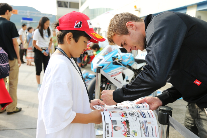 キッズピットウォーク: ファンの子供にサインをするジェームス・ロシター（KONDO RACING）