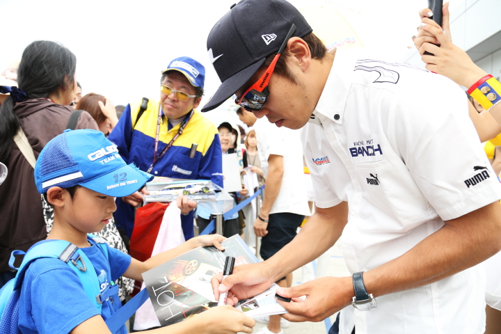 ピットウォーク: ファンの子供にサインをする中山友貴（UPGARAGE BANDOH 86）